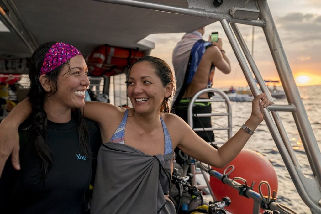 two female divers on boat at sunset