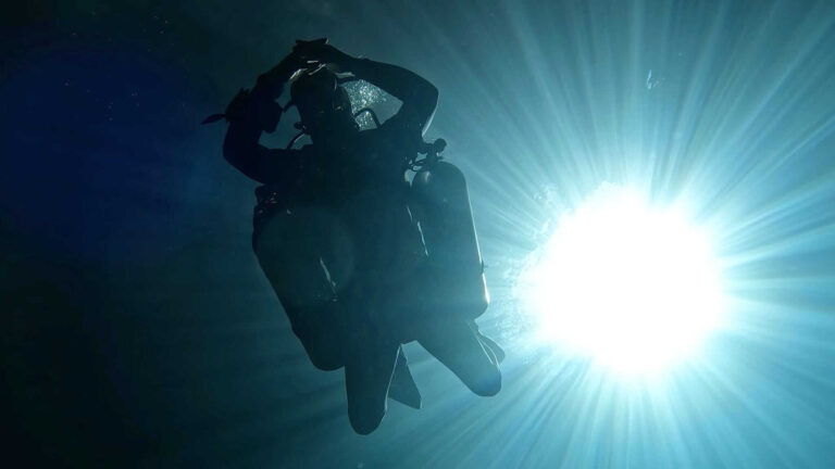 silhouette of scuba diver in sidemount