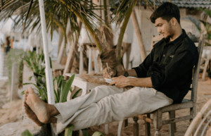 guy sitting at beach writing in notebook